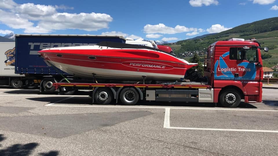 Autoarticolato Logistic Trans che trasporta una barca a vela lungo il lago